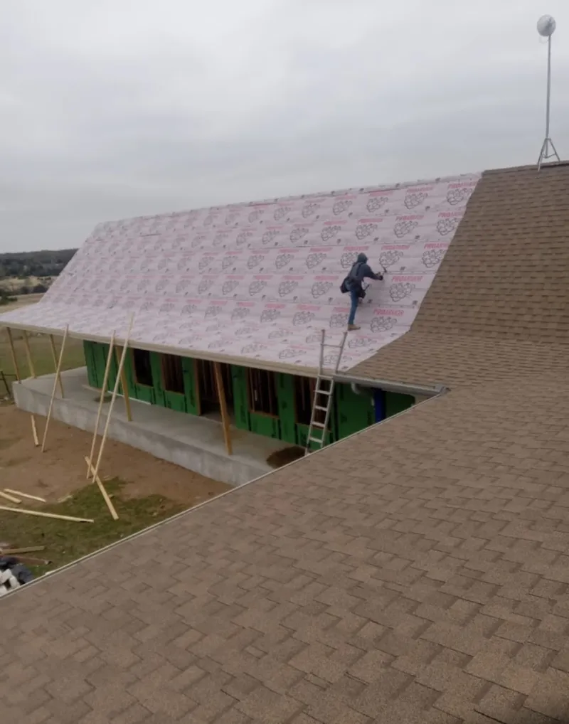 Worker preparing underlayment for a metal roof installation in Hampden